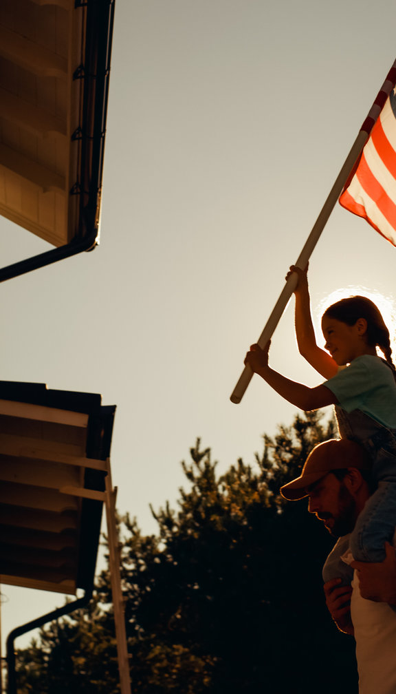 little girl putting the american flag up with her father