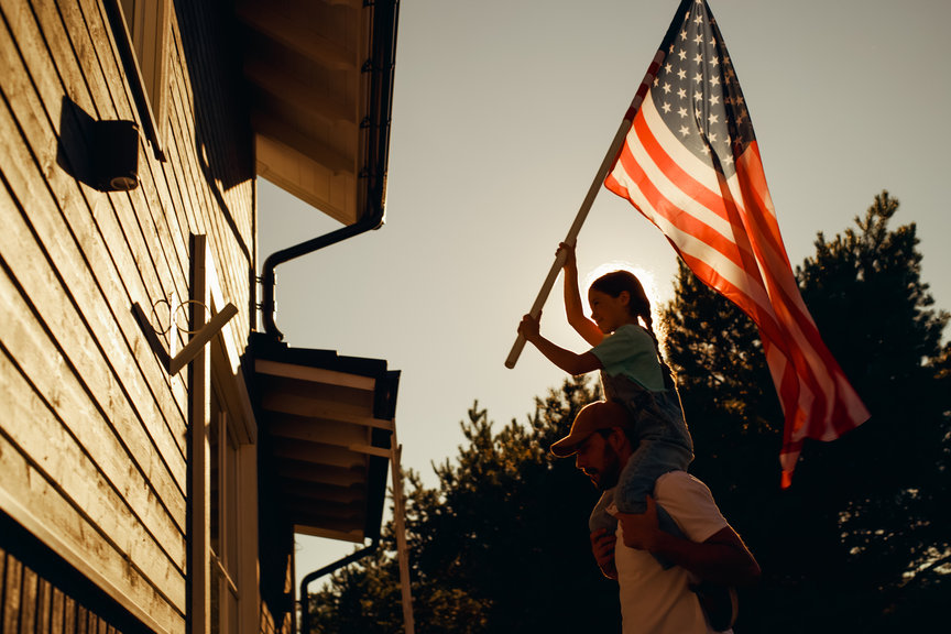 little girl putting the american flag up with her father